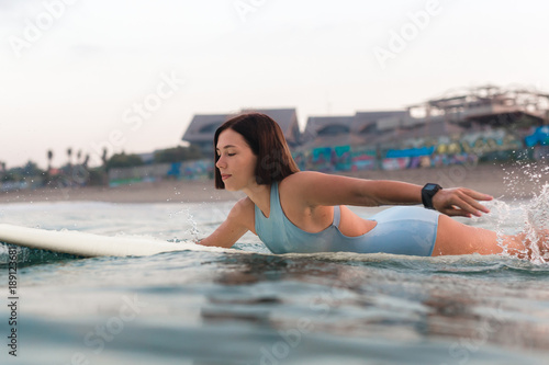 Photography Young woman in bright bikini surfing on a board in ocean