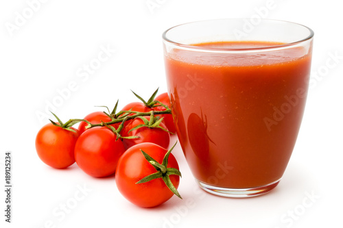 Ripe red tomatoes and tomato juice in a glass on white background  isolated.