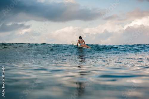 Canvas Print Young woman in bright bikini surfing on a board in ocean