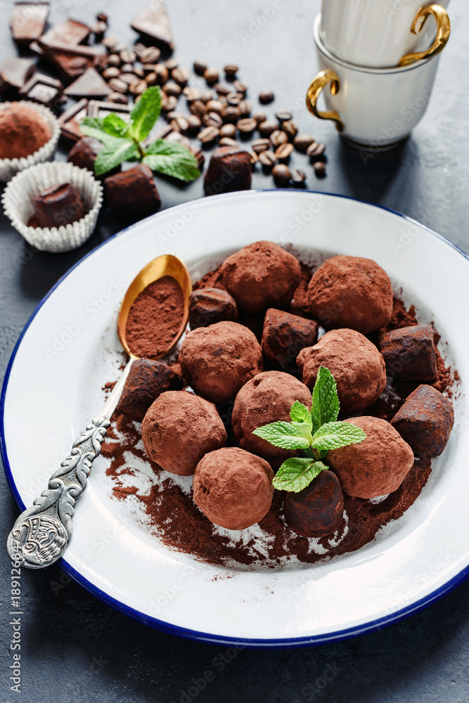 Chocolate truffes decorated with mint and ground cocoa on white plate. Selective focus, vertical image Chocolate truffes decorated with mint and ground cocoa on white plate. Selective focus, vertical image