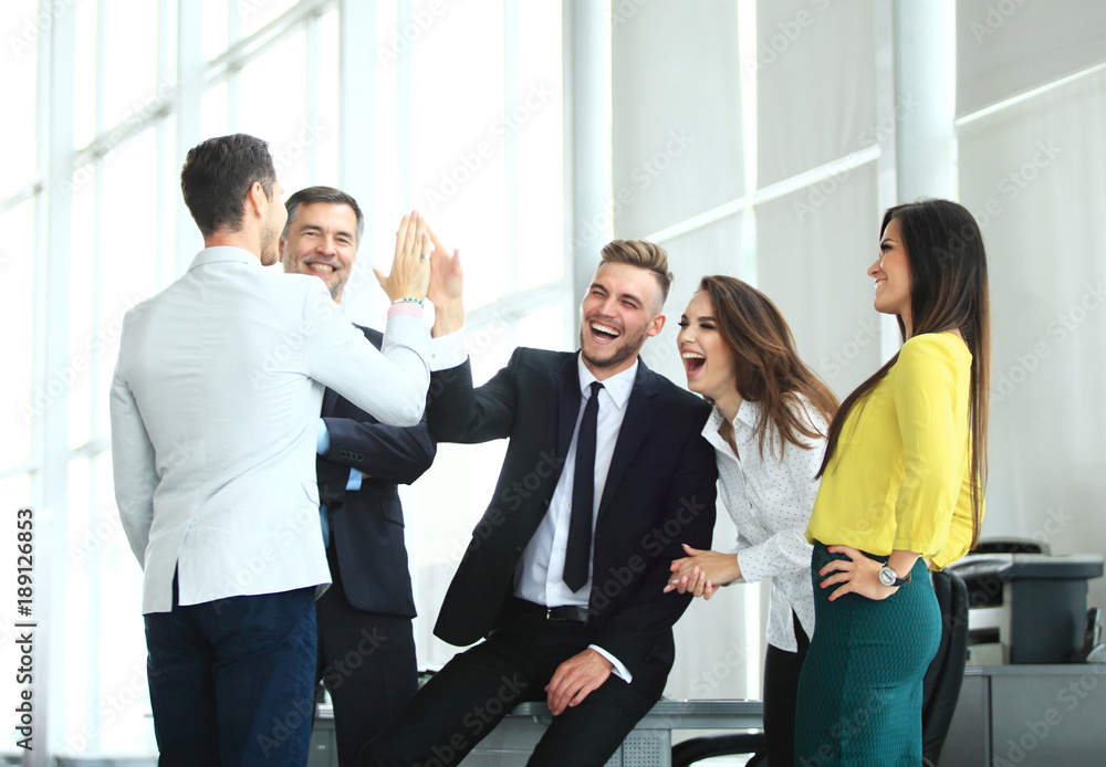 Happy successful multiracial business team giving a high fives gesture as they laugh and cheer their success Happy successful multiracial business team giving a high fives gesture as they laugh and cheer their success