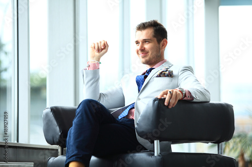 Low angle shot of a handsome young businessman in a stylish modern office space with large windows.