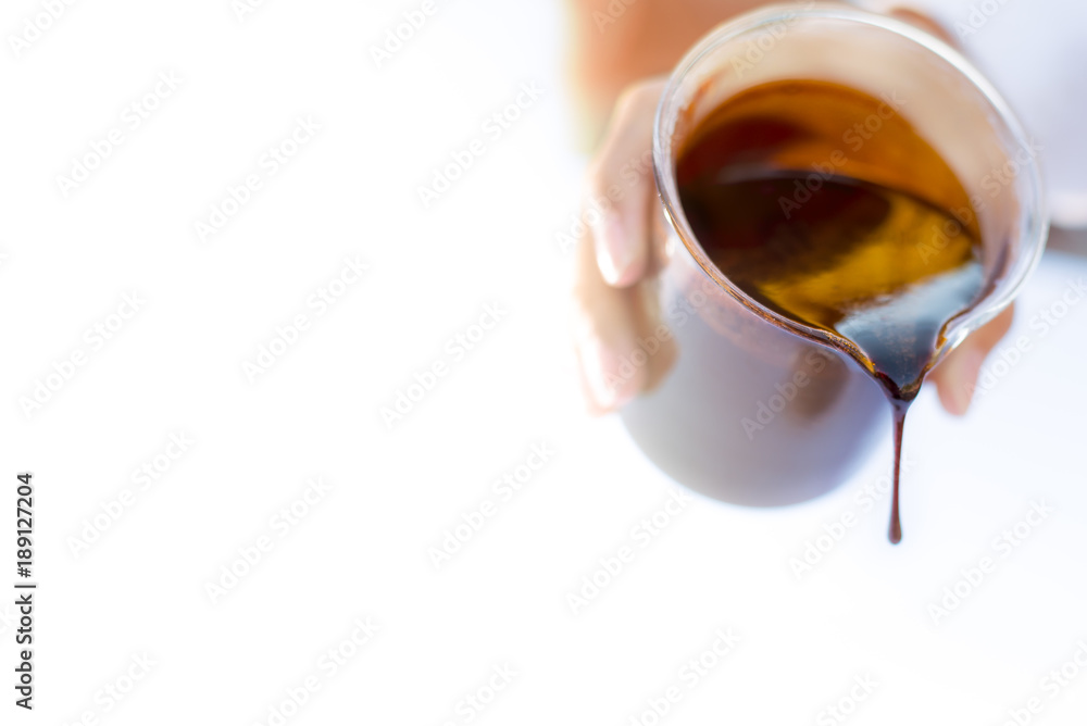 Molasses sugarcane on beaker. Droping molasses with hands. Molasses is