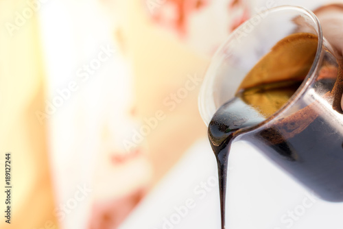 Molasses sugarcane on beaker. Droping molasses with hands. Molasses is the final product from the sugarcane extraction process of sugar factory. industrial concepts.