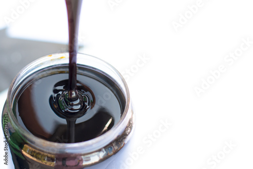 Molasses sugarcane on glass isolate on white background. Droping molasses with hands. Molasses is the final product from the sugarcane extraction process of sugar factory. industrial concepts.