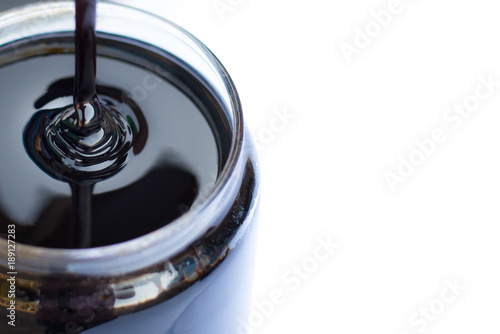Molasses sugarcane on beaker isolate on white background. Droping molasses with hands. Molasses is the final product from the sugarcane extraction process of sugar factory. industrial concepts.