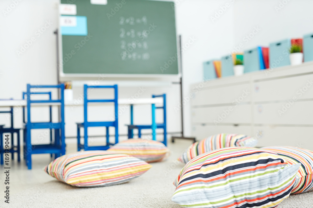 Naklejka premium Empty classroom in modern school with soft striped pillows on the floor