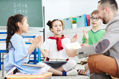 Foto Diligent schoolkids learning rhymes by heart while repeating them after teacher