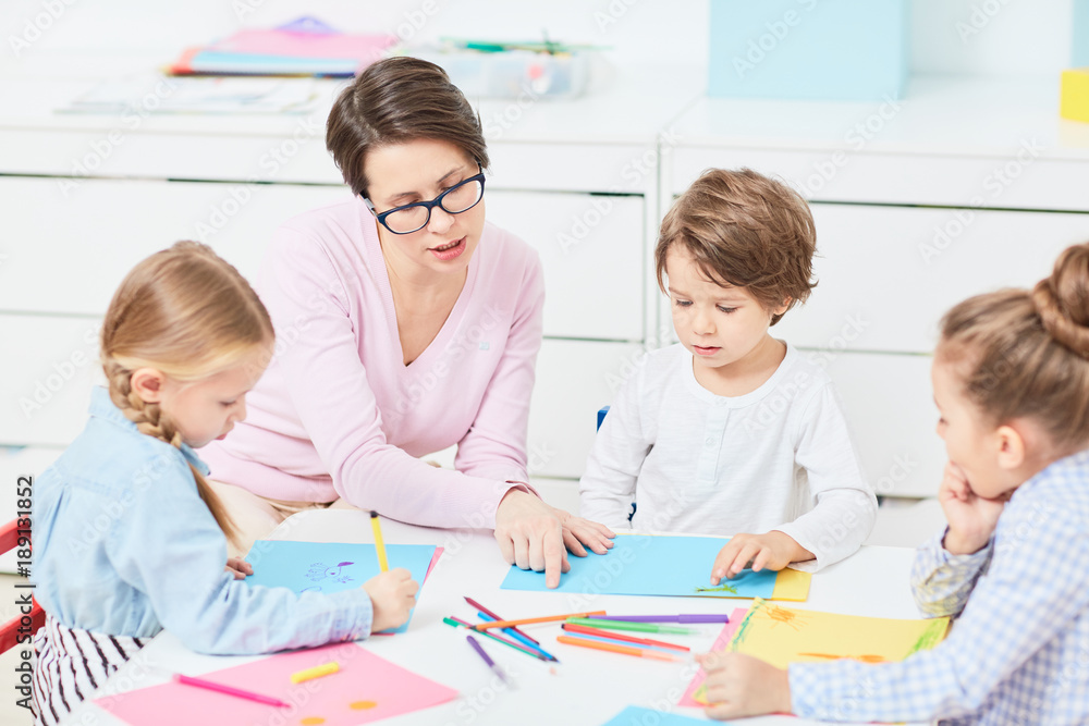 Young teacher explaining little boy how to draw and what to start with