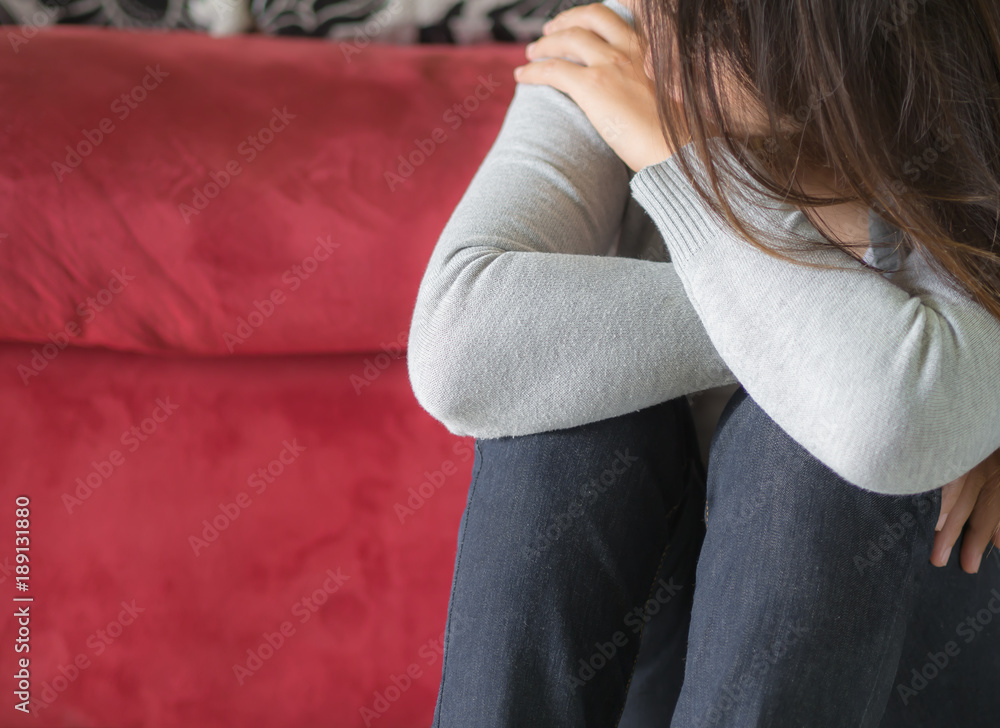 Depressed woman sitting by sofa at home. Depressed woman sitting by sofa at home.