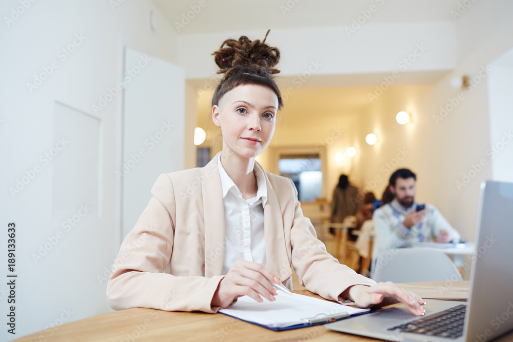 Contemporary young professional accountant sitting by workplace, working with documents and browsing in the net Contemporary young professional accountant sitting by workplace, working with documents and browsing in the net