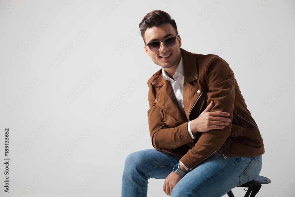 smiling fashion man sitting and holds his elbow smiling fashion man sitting and holds his elbow