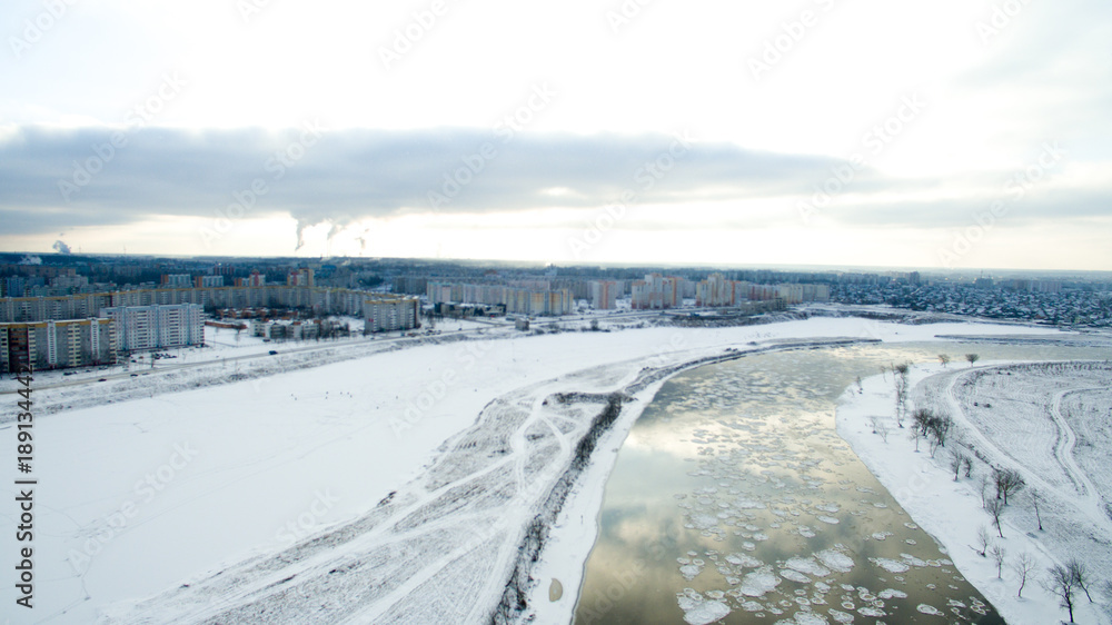 Ice swims in the river. Winter landscape photographed from above near the city. Top view. Nature and abstract background