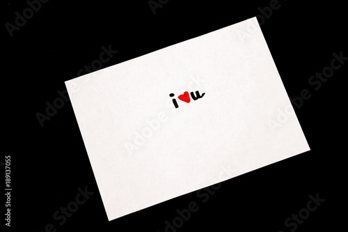 I Love You message hand written in marker with red heart shape on white paper. Black background. For Valentine's Day or any time.