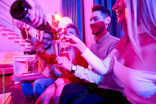 Canvas Print Side view at group of glamorous  people enjoying private party, sitting on sofa
