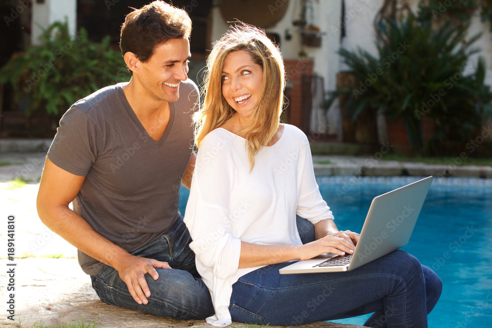 couple sitting outside together by pool with laptop couple sitting outside together by pool with laptop