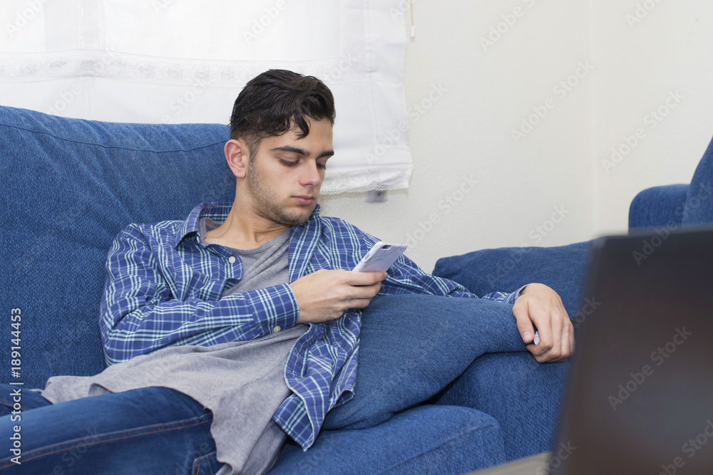 Obraz premium young at home with the mobile phone on the couch