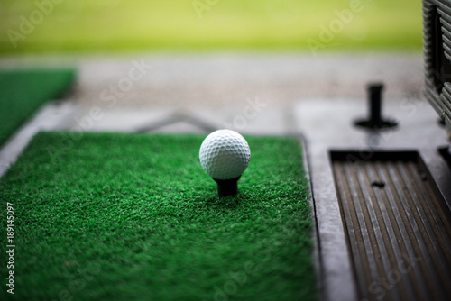 Golf ball on artificial green grass place with tee for practice Driving Range