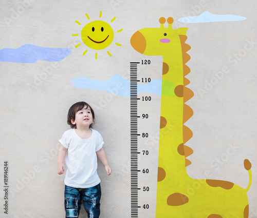Canvas Print Closeup asian kid stand for measure height and look at cute giraffe cartoon at t