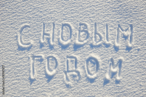 Happy New year text written on russian language on snow for texture or background - winter holiday concept. Sunny day, bright light with shadows, flat lay, top view, clean and nobody