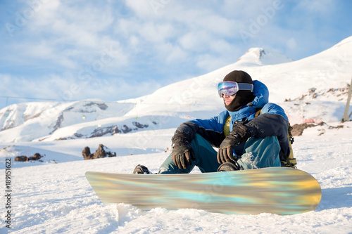 Smiling man snowboarder resting sit