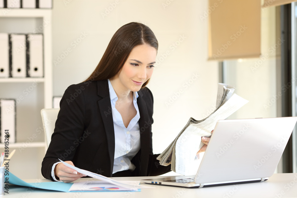 Office worker comparing online content with a newspaper Office worker comparing online content with a newspaper