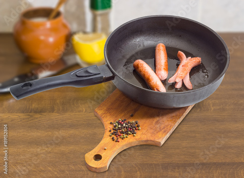 Canvas Print Fried vienna sausages in the frying pan on cook table