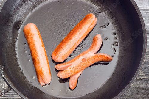 Canvas Print Fried vienna sausages on the frying pan closeup