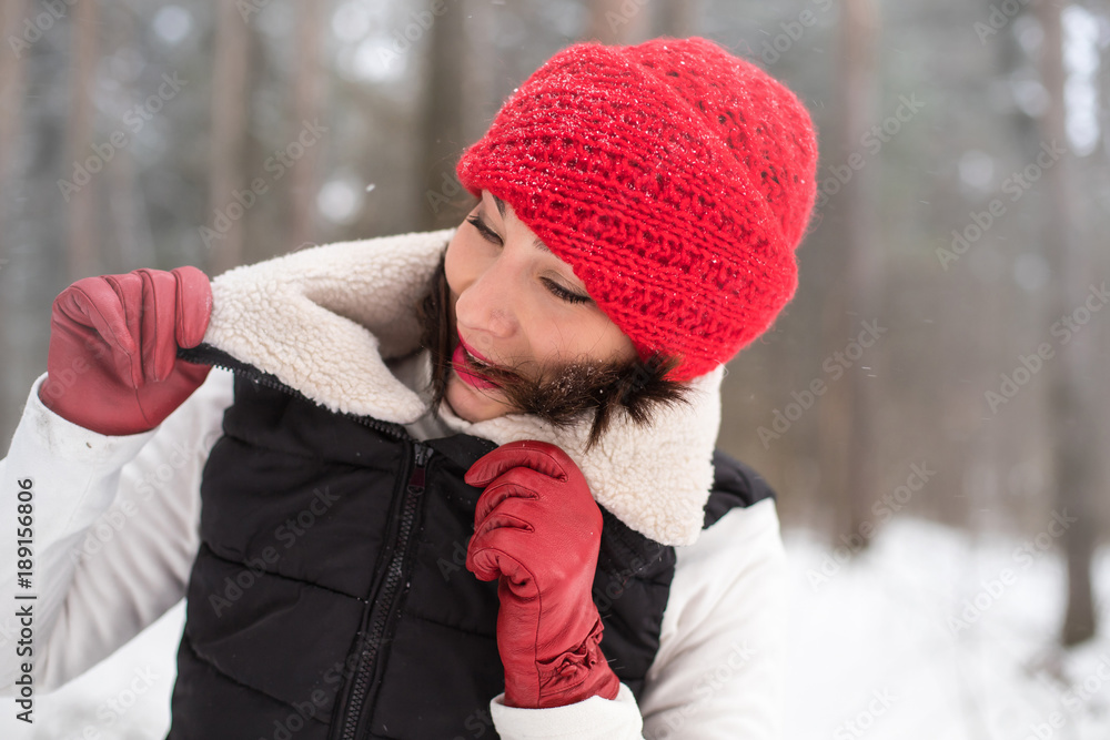 Portrait of girl in a red cap and warm jacket in the forest in a winter Portrait of girl in a red cap and warm jacket in the forest in a winter