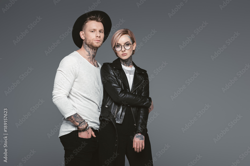stylish tattooed couple posing together, isolated on grey stylish tattooed couple posing together, isolated on grey