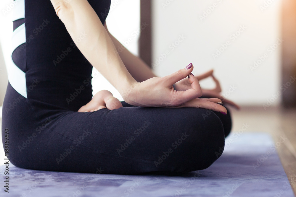 Young woman meditating indoors at home in lotus pose. Yoga hands close-up