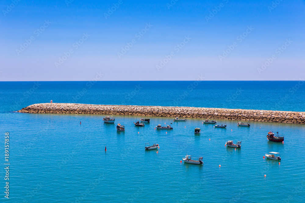 Many small boats lying near jetty in sea