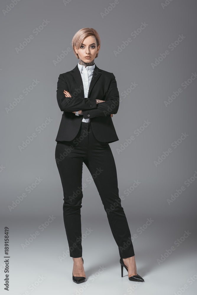 businesswoman posing in suit with crossed arms, isolated on grey businesswoman posing in suit with crossed arms, isolated on grey