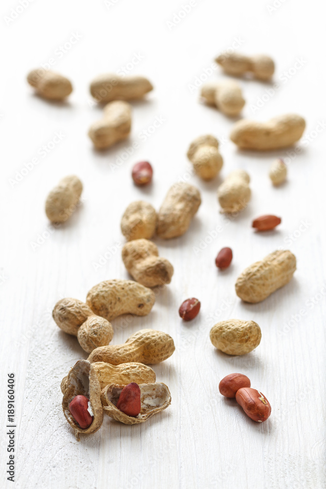 Obraz premium Handful of peanuts in shell on a white table