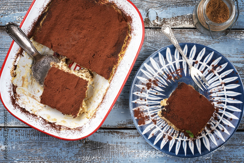 Traditional Italian tiramisu as top view on plate and in backing form photo