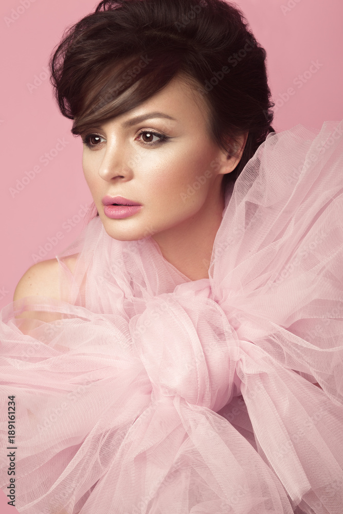 Fashion beautiful woman in black dress with bow, retro make-up and hair. Beauty face and body. Photo taken in studio on a pink background Fashion beautiful woman in black dress with bow, retro make-up and hair. Beauty face and body. Photo taken in studio on a pink background