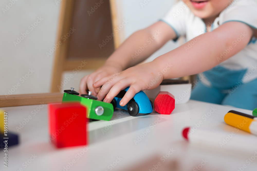 The little toddler boy using imagination to assemble toy train to cultivate ideas, close up on hands