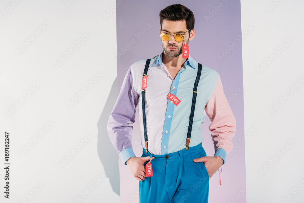 handsome stylish young man in sunglasses with sale labels on grey handsome stylish young man in sunglasses with sale labels on grey