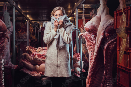 A woman in a warm jacket in a meat freezer storage.