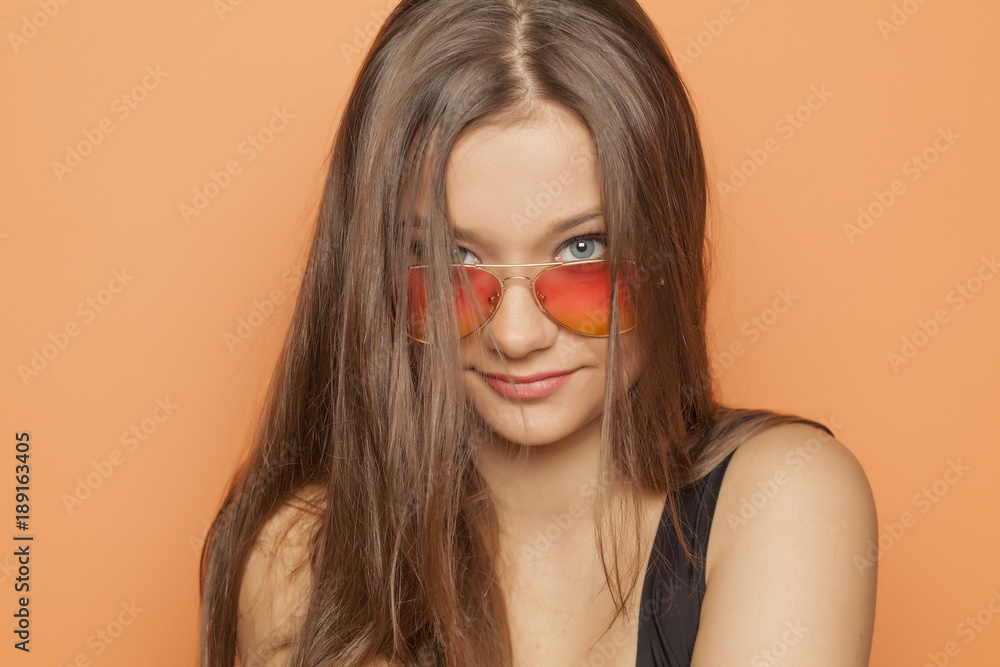 young smiling girl with orange sunglasses on orange background young smiling girl with orange sunglasses on orange background