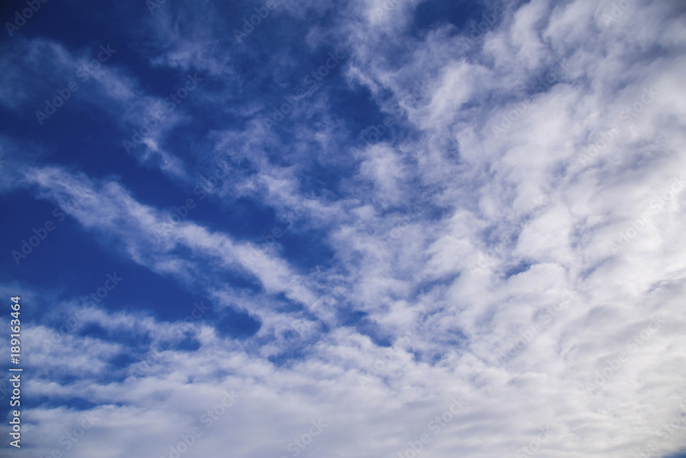White spindrift clouds on blue sky, background
