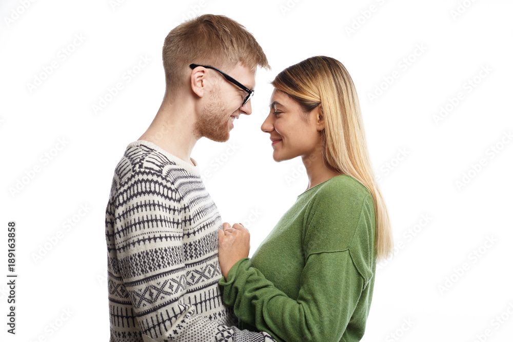 Profile portrait of happy joyful young male and female in love standing close to each other, hugging and talking, smiling cheerfully, feeling relaxed and carefree, dressed in stylish clothes Profile portrait of happy joyful young male and female in love standing close to each other, hugging and talking, smiling cheerfully, feeling relaxed and carefree, dressed in stylish clothes