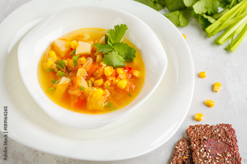 Healthy bright vegetable corn soup in a white plate with flax crispy bread. Vegan Healthy Food Concept. Top view Healthy bright vegetable corn soup in a white plate with flax crispy bread. Vegan Healthy Food Concept. Top view