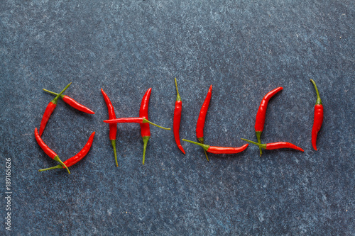 Word "chilli" from small red chili peppers on a blue background. Vegetable background. Copy space