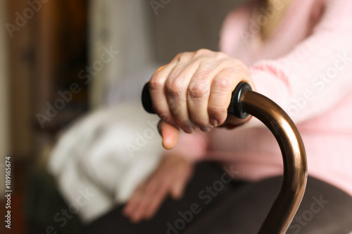 Close up of elderly woman holding a walking cane in nursing home.