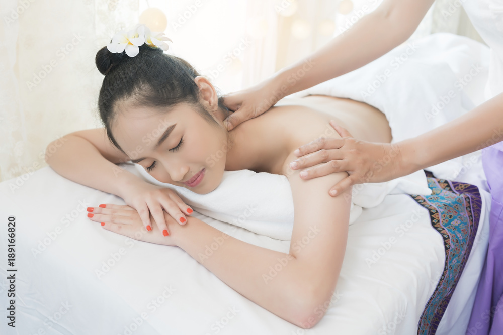 Beautiful young Asian woman relaxing , lying on massage table and having Thai traditional massage in spa salon Beautiful young Asian woman relaxing , lying on massage table and having Thai traditional massage in spa salon