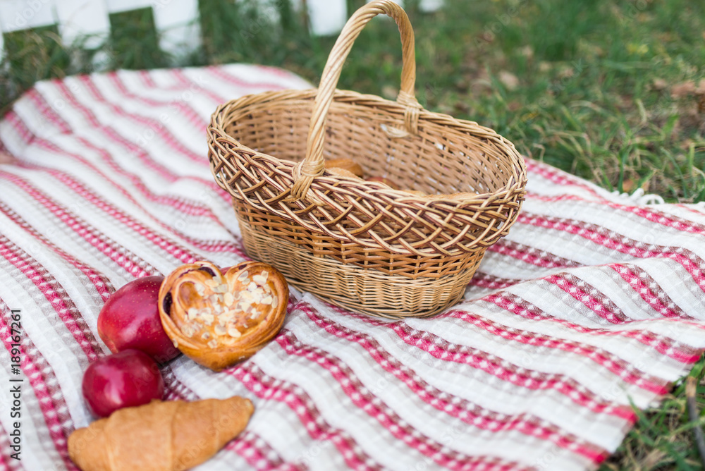 Romantic picnic in the garden - a basket with bakery and apples. Picnic on the lawn. Objects for picnic on a coverlet. Weekend. Romantic picnic in the garden - a basket with bakery and apples. Picnic on the lawn. Objects for picnic on a coverlet. Weekend.