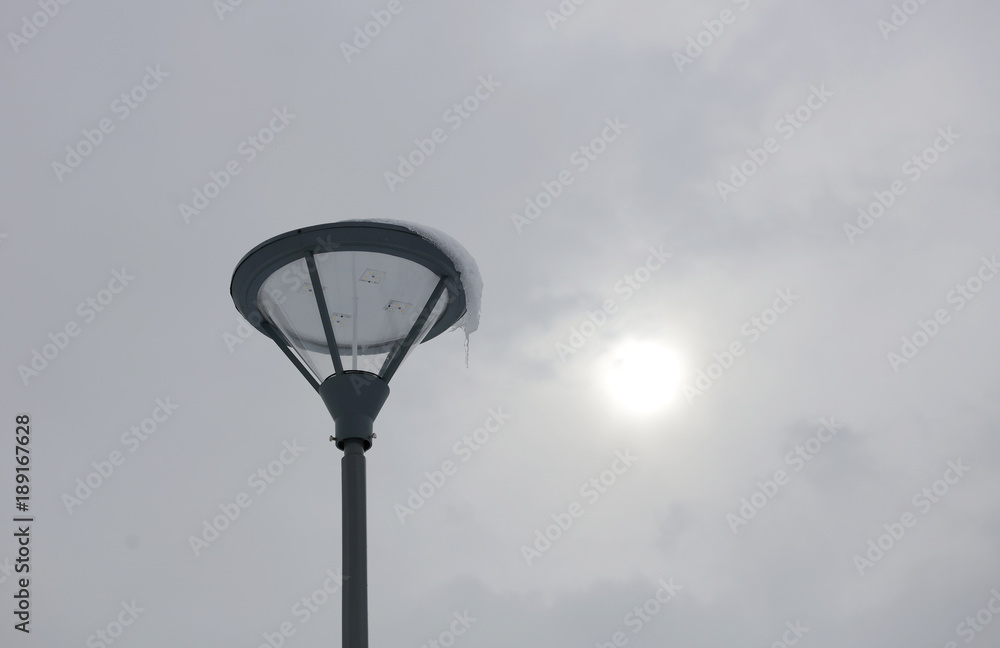 LED street light with grey pole and armature aigainst white winter sky. LED street light with grey pole and armature aigainst white winter sky.