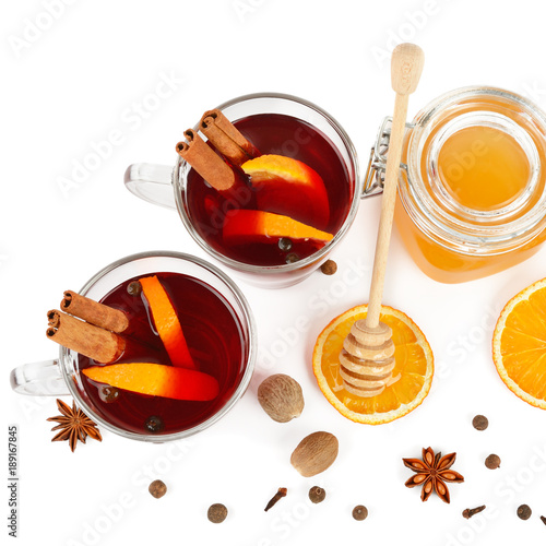 Hot red mulled wine, bee honey, slices of oranges and spices isolated on white background.