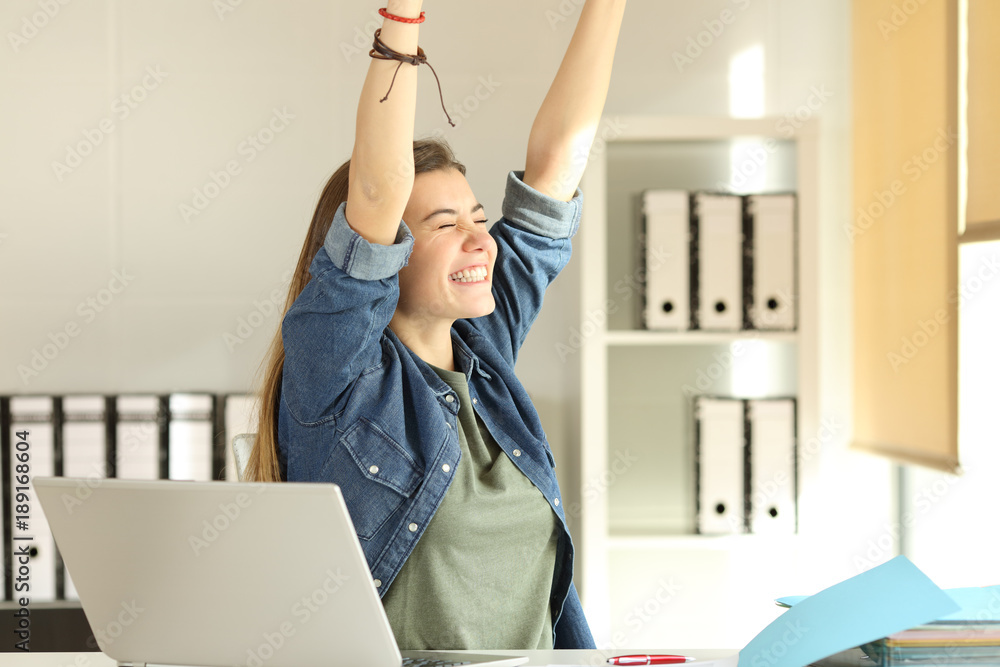 Satisfied intern raising arms at office - obrazy, fototapety, plakaty 